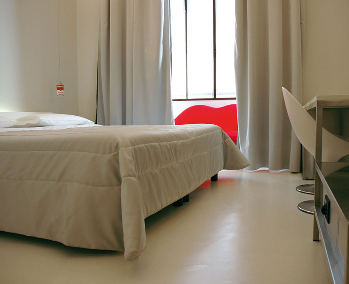 Schlafzimmer mit fugenlosem hellgrauem Bodenbelag und minimalistischer Einrichtung