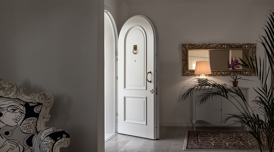 Weiße Sicherheitstür mit Rundbogen und goldenen Details in klassischem Interieur