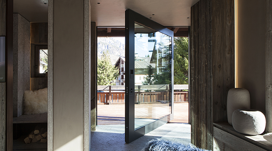 Moderne Glastür mit Ausblick auf Chalet-Terrasse in den Bergen