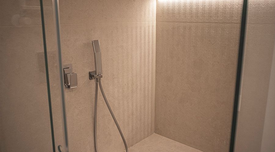 Fugenlos geflieste Dusche mit texturierten, naturfarbenen Keramikplatten